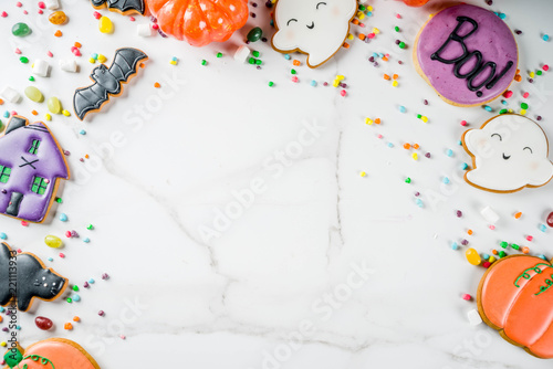 Traditional Halloween baked pastry, funny cookies and candies for children's treat - ghost, pumpkins, black cat, bats, witch house. White background, top view copy space 