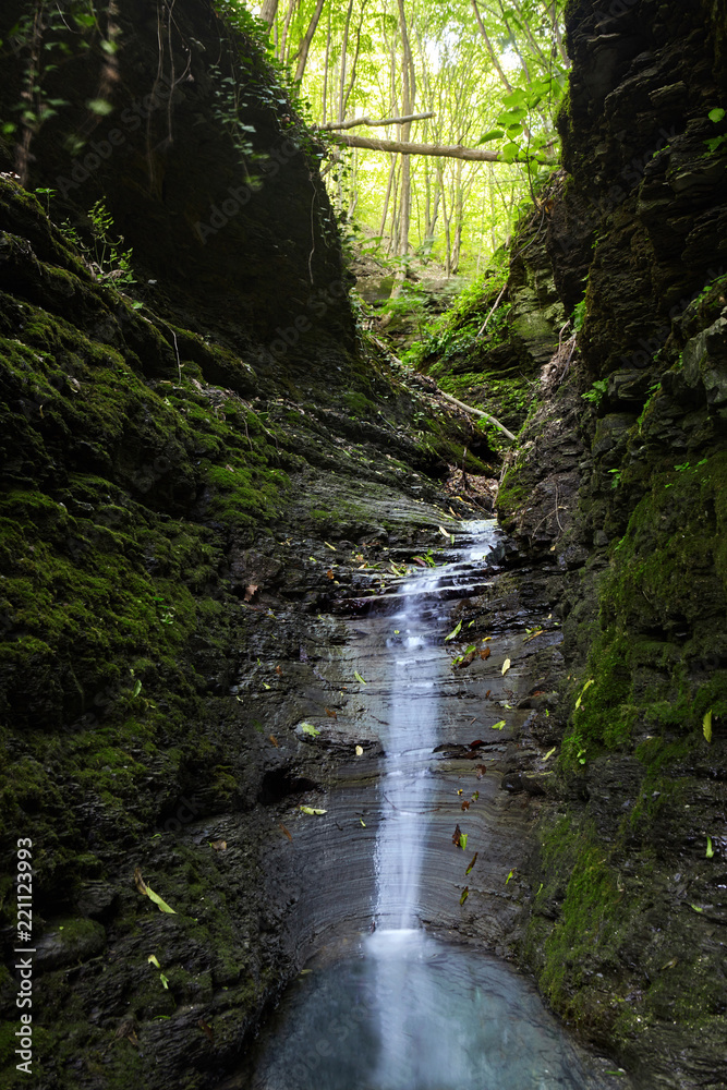Cascade falls over mossy rocks. Spring in forest.magic lightnings.Deep forest athmosphere. Cascade falls over mossy rocks. Spring in forest.magic lightnings.Deep forest athmosphere.