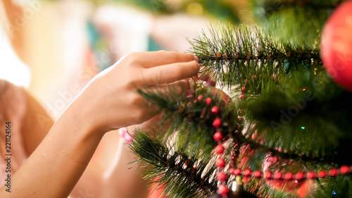 Closeup image of young girl hanging baubles on Christmas tree branches