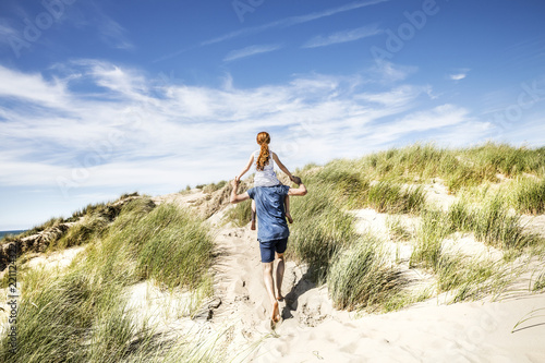 Netherlands, Zandvoort, father carrying daughter on shoulders in beach dunes photo