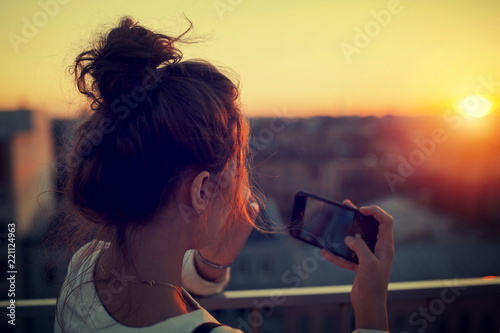 stylish girl is shooting the sunset by the phone