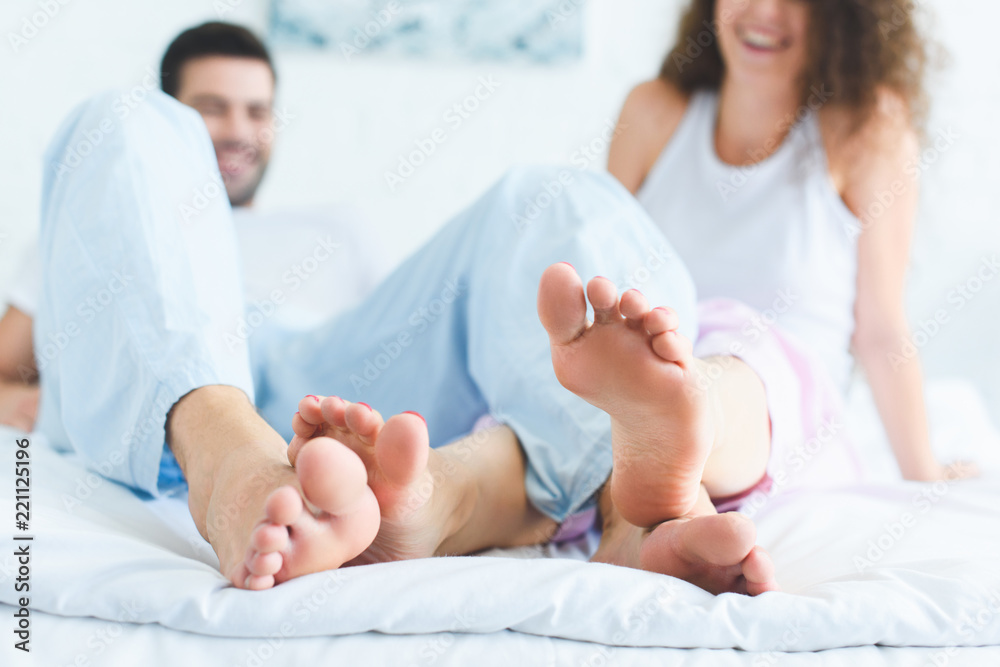 close-up view of feet of happy young couple on bed at morning close-up view of feet of happy young couple on bed at morning