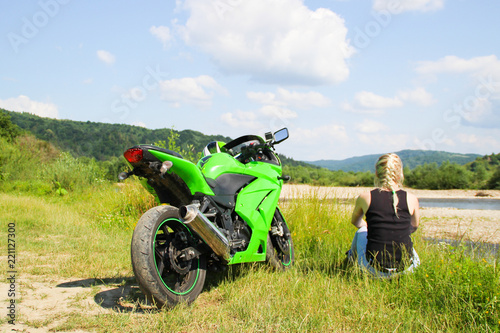 Green sport motorbike on the background of mountains with blond girl. Motorcycle on the nature. Ukraine