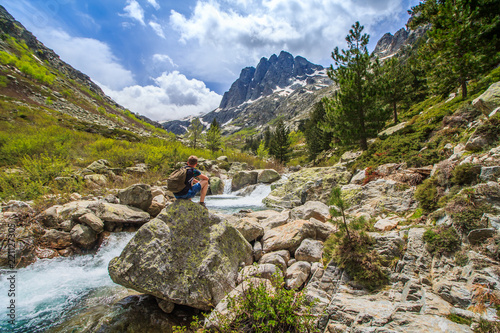 Tableau sur toile Man traveler with backpack hike across the river in Corsica natural park