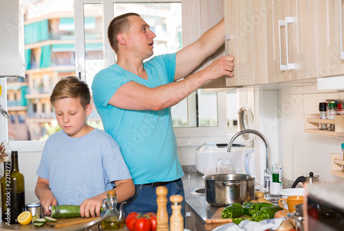 Boy and his father are cooking soup together in the kitchen