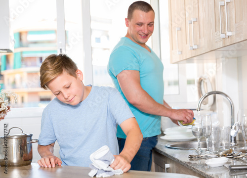 Man with his son are washing dishes on the kitchen
