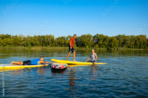 Obraz na płótnie Joyful friends, a SUP surfers relax on the big river w salonie