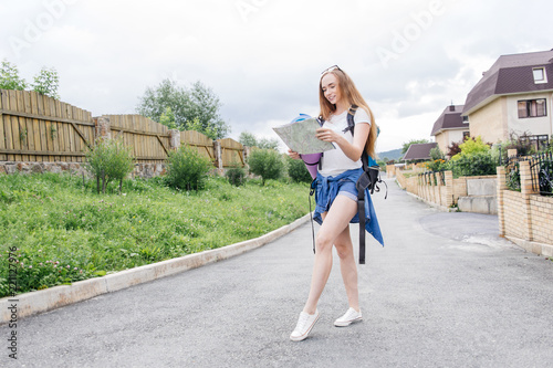 Beautiful woman traveler holding location map in hands in a city