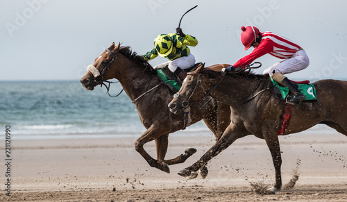 Two race horses and jockeys racing on the beach, the wild atlantic way on the west coast of Ireland