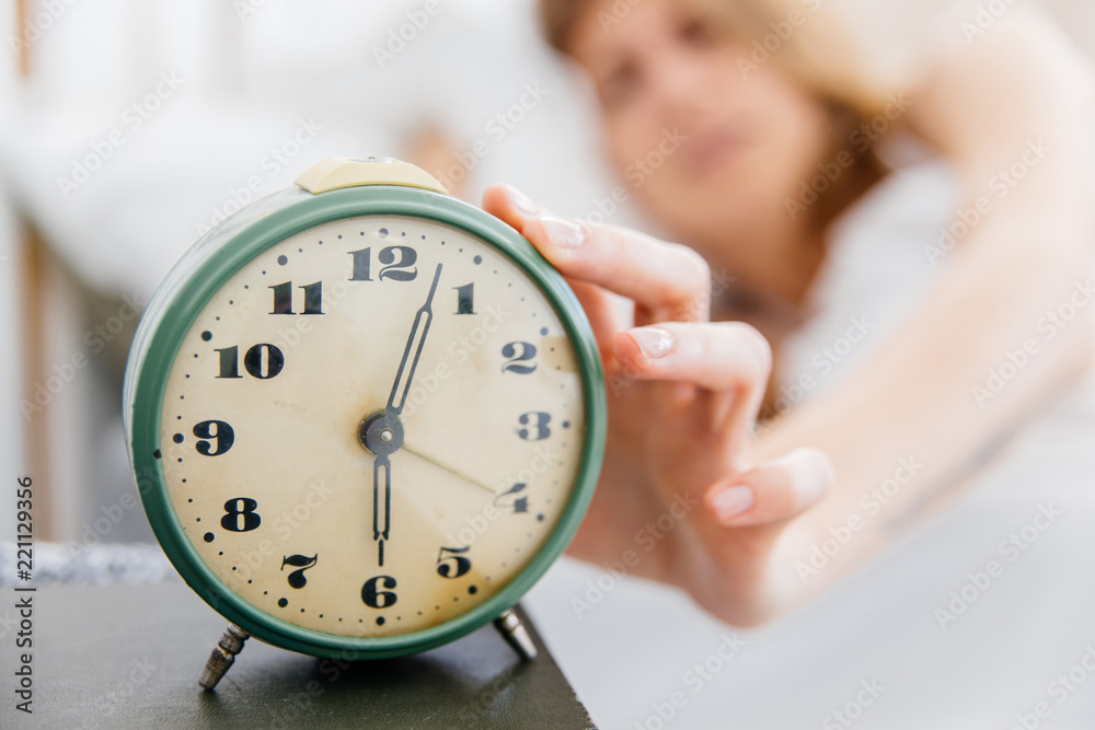 Young woman turns off the alarm clock in the morning Young woman turns off the alarm clock in the morning