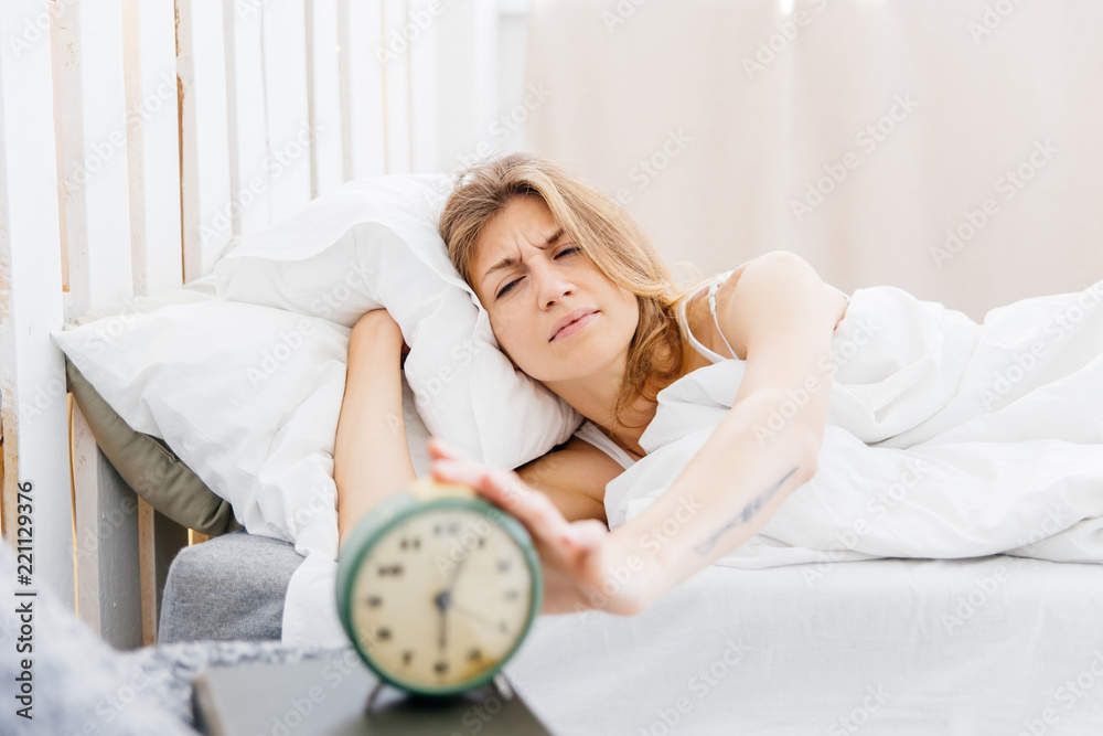 Young woman turns off the alarm clock in the morning Young woman turns off the alarm clock in the morning