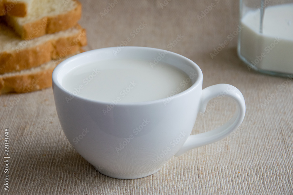 A cup of milk and pieces of white bread.