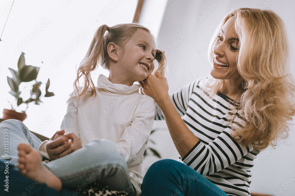 Pleasant emotions. Joyful happy girl looking at her mother while smiling to her