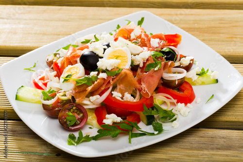 Dish of Bulgarian cuisine shepherd's salad with fresh vegetables, salmon and quail eggs