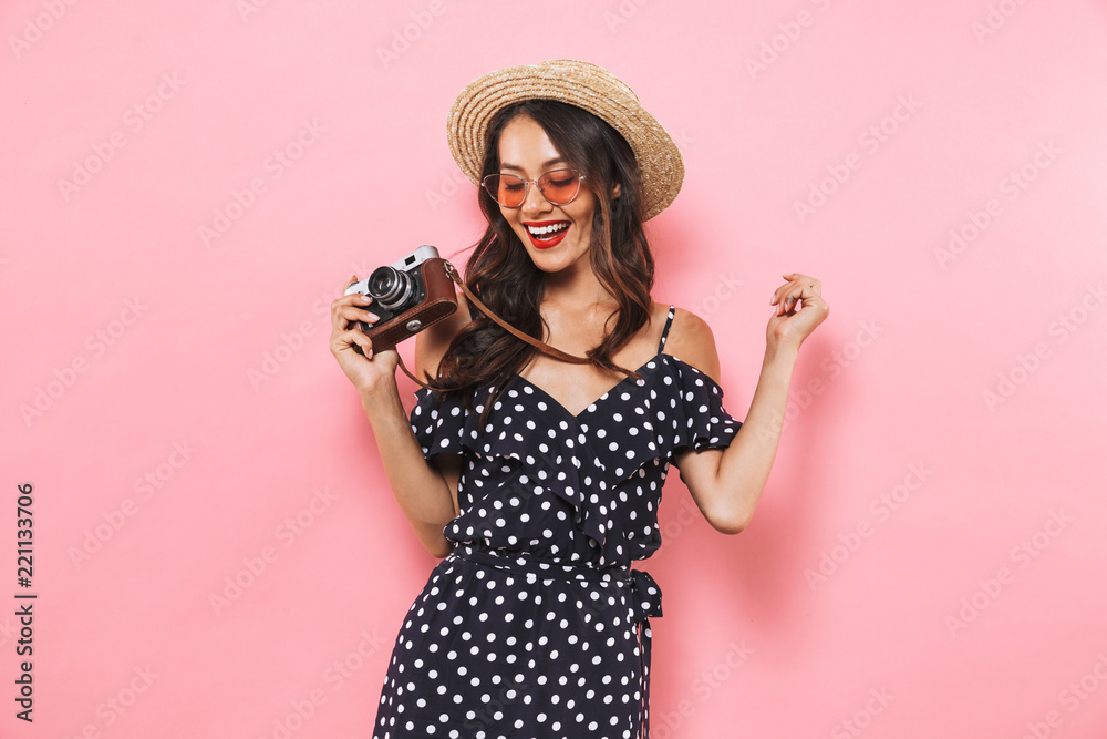 Fototapeta premium Smiling brunette woman in straw hat and sunglasses making photo