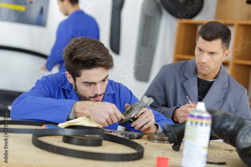 man with apprentice holding car part