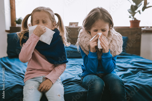 Being ill. Depressed young girls using paper tissues while being sick photo
