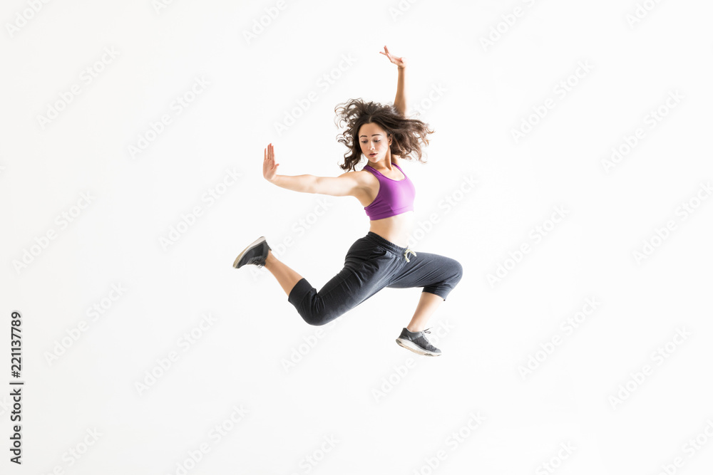 Fototapeta premium Woman In Midair Practicing Ballet Moves Against White Background