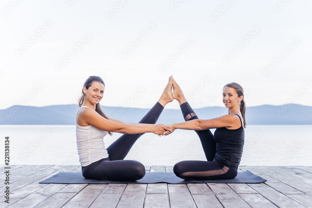 Young attractive smiling women practicing yoga on a lake Young attractive smiling women practicing yoga on a lake