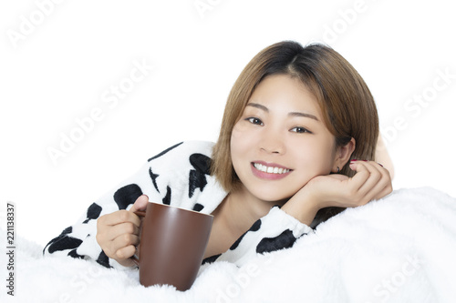 Chinese woman laying in bed drinking coffee on white background
