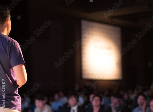 Presenter Giving Presentation to Group of People from Stage at Conference Event. Trainer Speaker Giving Lecture Speech. Teacher Education on Business and Technology. Blurred.