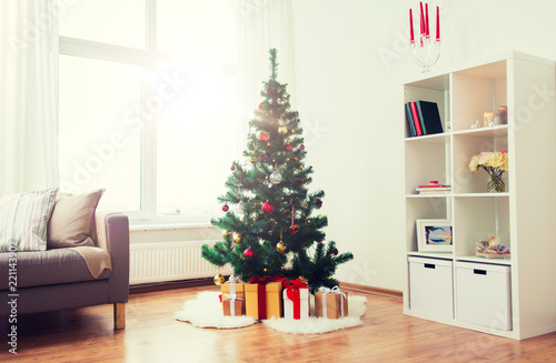 holidays and interior concept - artificial christmas tree and presents at home living room