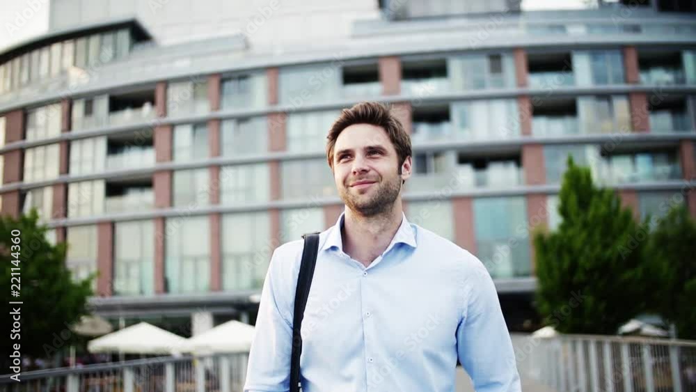 A young businessman with a bag walking on a bridge. A young businessman with a bag walking on a bridge.