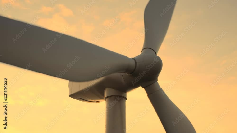 Offshore wind turbines spinning around at the sun setting background. Closeup