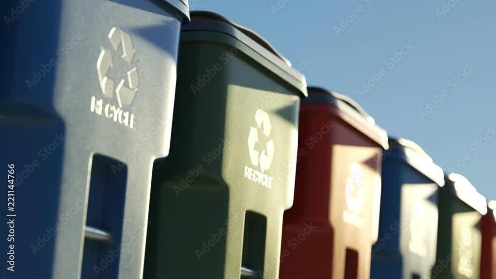Colorful plastic garbage bins stacked in a row against a clear sky background.