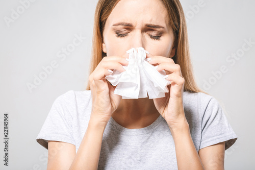 People, healthcare, rhinitis, cold and allergy concept - unhappy woman with paper napkin blowing nose