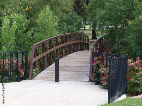 A bridge covers a stream below linking a water park and rec center to a park for picnics and sports fields, The landscaping contains sculptures and art,too.