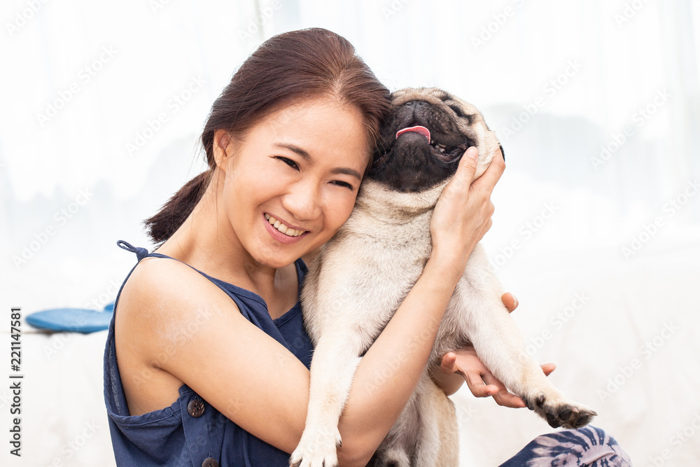 Beautiful Asian young woman playing with her dog and smile with dog pug breed looking in funny face in bedroom,Friendship Concept Beautiful Asian young woman playing with her dog and smile with dog pug breed looking in funny face in bedroom,Friendship Concept
