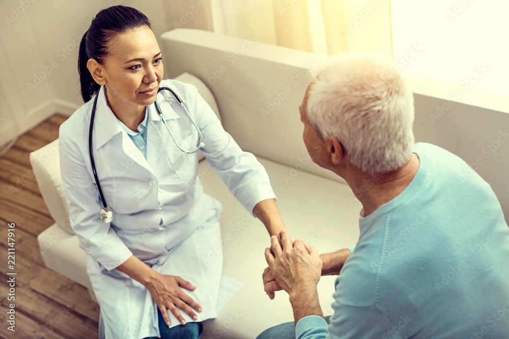 Obraz premium Moment of gratitude. Selective focus on a thoughtful female nurse looking at a thankful senior gentleman and listening to him during a consultation.