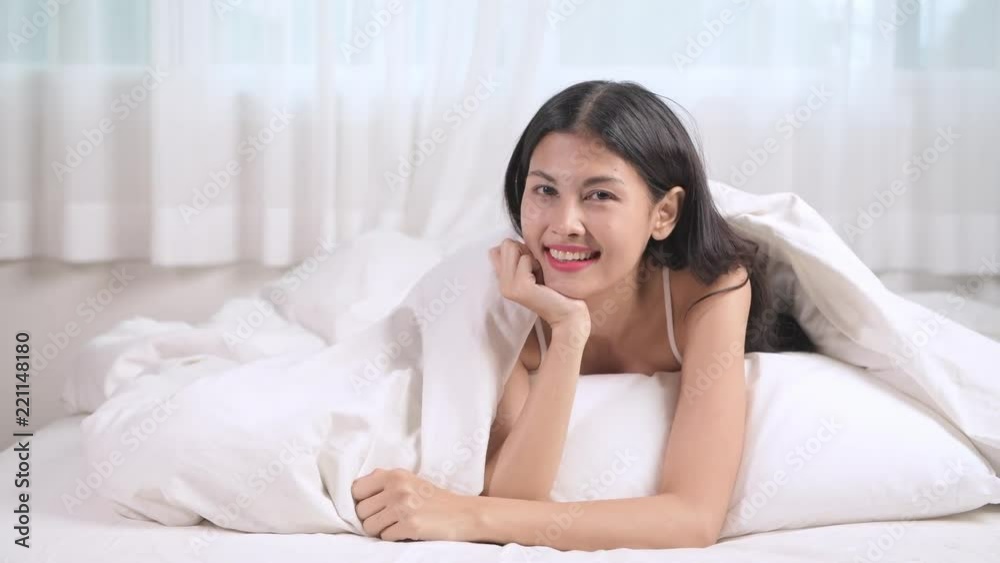 Attractive woman in bed portrait. Asian woman lying in bed smiling. Attractive woman in bed portrait. Asian woman lying in bed smiling.