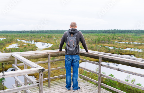 Tourist stopped on bridge with backpack to enjoy nature in summer day.