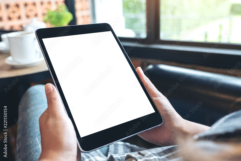 Mockup image of hands holding black tablet pc with blank white desktop screen while sitting in cafe Mockup image of hands holding black tablet pc with blank white desktop screen while sitting in cafe