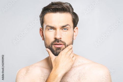 Photo of young man standing isolated over grey wall background naked. Skincare concept.