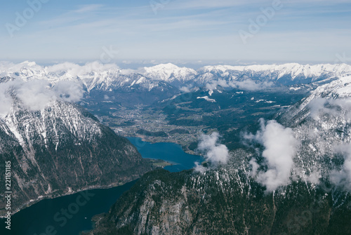 Spectacular view of snowy mountain peaks in Austrian Alps. Clouds flying above evergreen forests. Beautiful dreamy landscape.