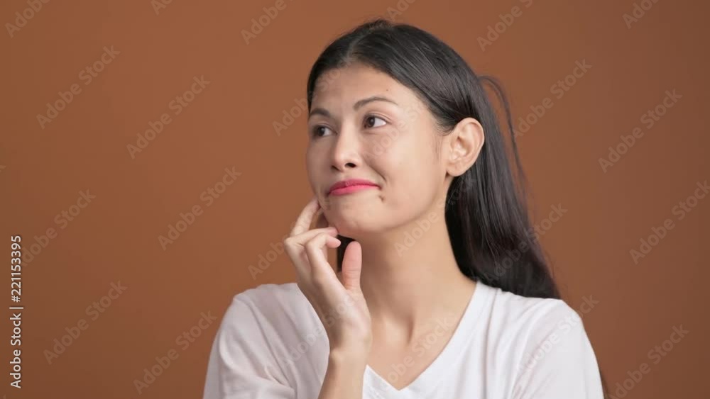 Asian woman portrait in orange background. White t-shirt, smiling at camera. Asian woman portrait in orange background. White t-shirt, smiling at camera.