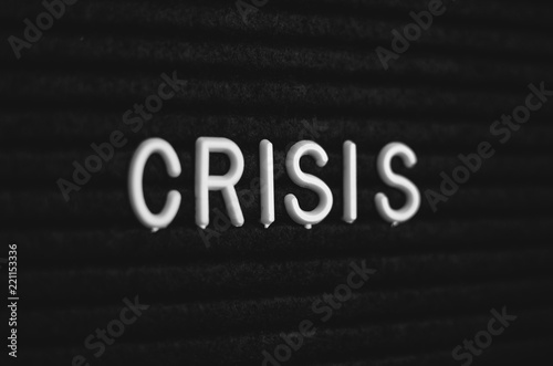 Word crisis written on the letter board. White letters on the black background