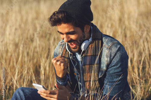 Young happy man using a smartphone in nature
