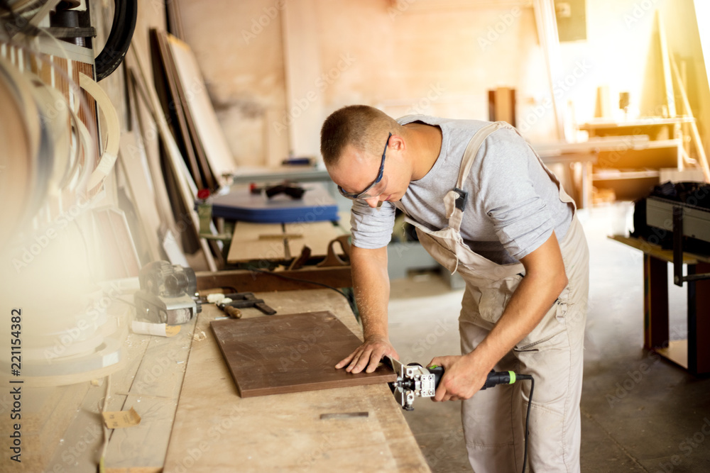 Carpenter working on woodworking machines in carpentry shop