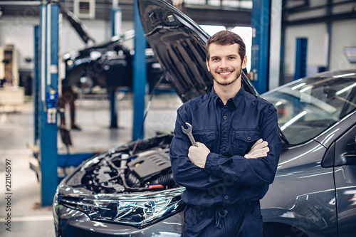 Auto car repair service center. Happy mechanic standing by the car photo