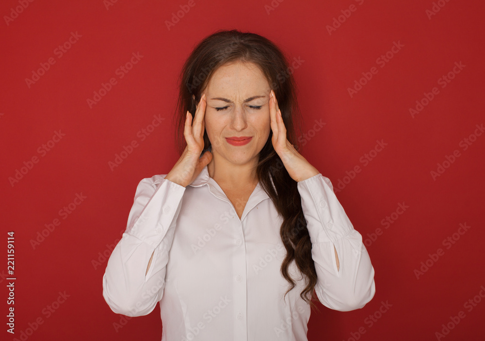 A businesswoman with a headache holding head, isolated on red background A businesswoman with a headache holding head, isolated on red background