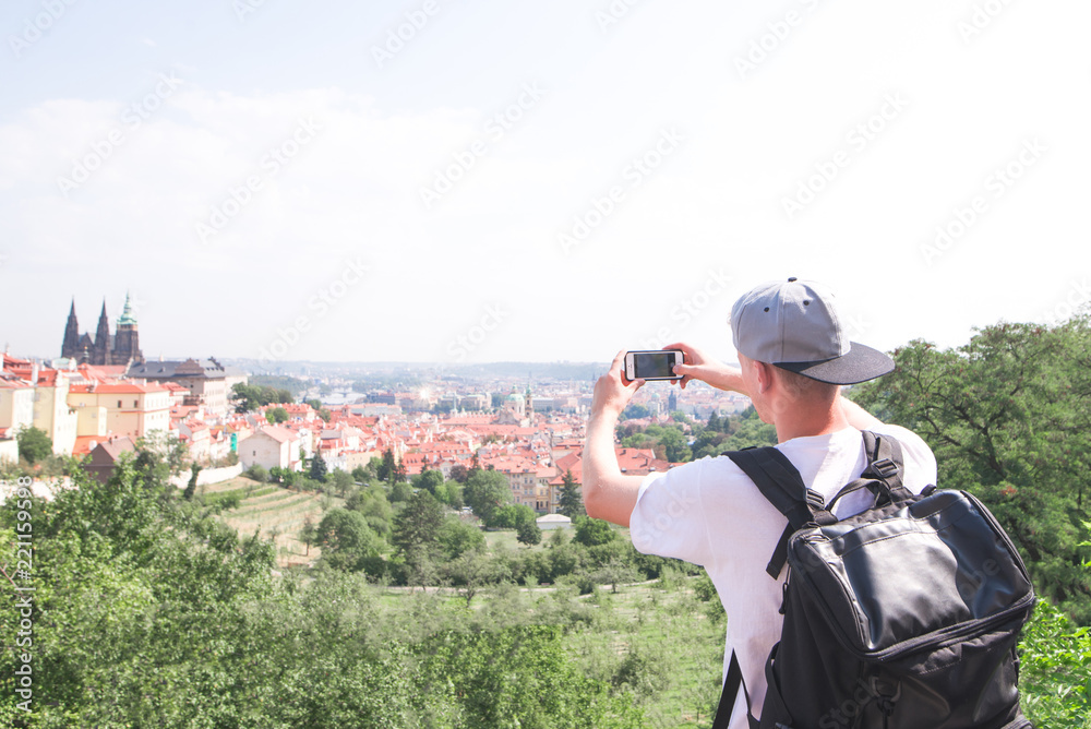 Young man photographs Prague from the observation deck. Tourist in Prague photographs landscapes on a smartphone. Young man photographs Prague from the observation deck. Tourist in Prague photographs landscapes on a smartphone.