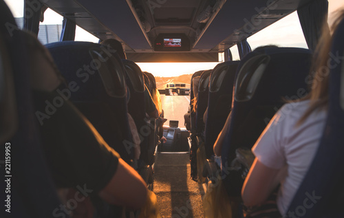 People ride in the bus at sunset. Salon bus with tourists. Selective focus of the bus interior with tourists at sunset.