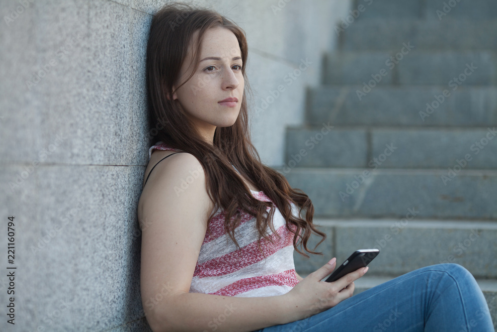 Image of beautiful stylish woman sitting on street stairs on summer day and holding mobile phone Image of beautiful stylish woman sitting on street stairs on summer day and holding mobile phone