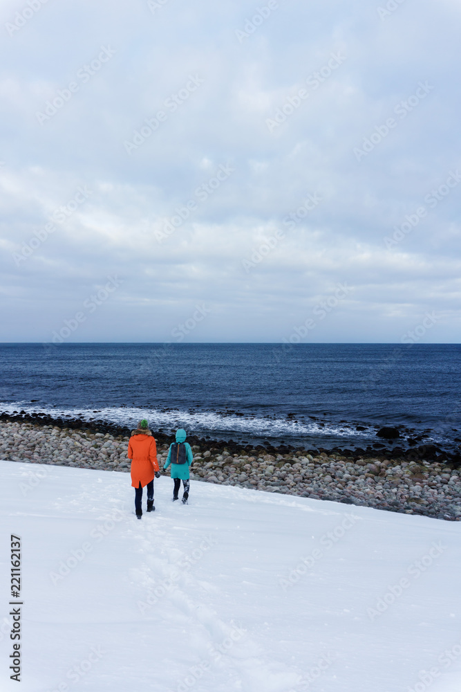 Φωτογραφία two girls in bright colored insulated kurts stand on the shore of the Arctic Ocean beyond the Arctic Circle