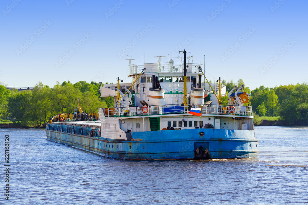 Industrial boat on the river a background of green trees on the shore