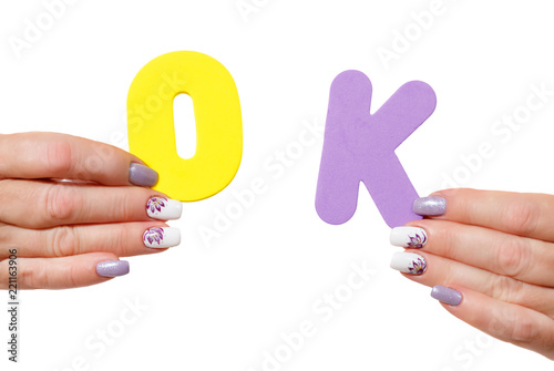 hands of woman with manicure hold letters ok